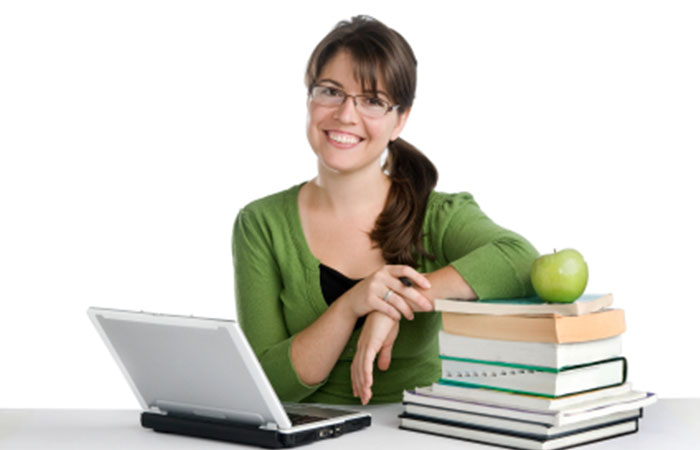 Engelsk lærer med laptop i grøn trøje ved et bord med bøger