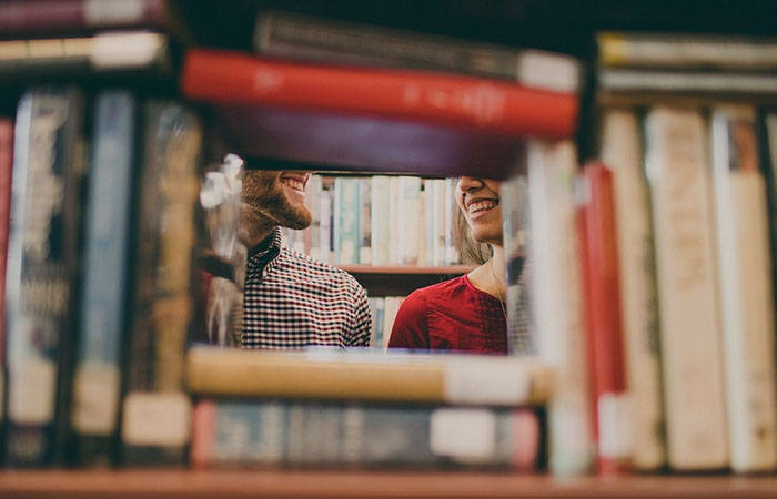 To elever snakker sammen bag hylde på biblioteket