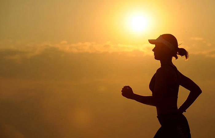 Kvinde løber i solnedgangen med orange baggrund