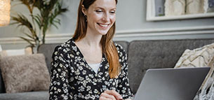 Foto af ung kvinde som underviser online via bærbar computer i sin stue - grå nuancer